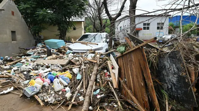 Debris piled up in front of a white car