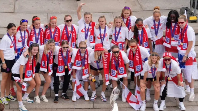 England players gather on the steps of the Victoria Memorial during a Homecoming Victory Parade.