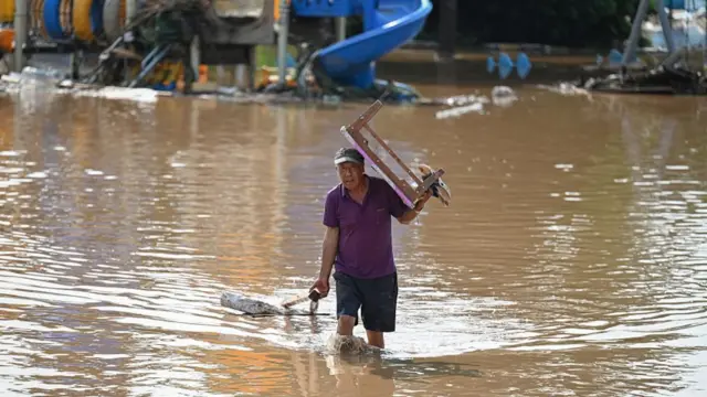 A man carries a table while walking through a flood in Miyun Beijing China