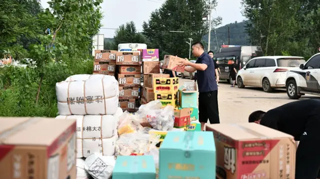A man standing beside stacks of boxes of food