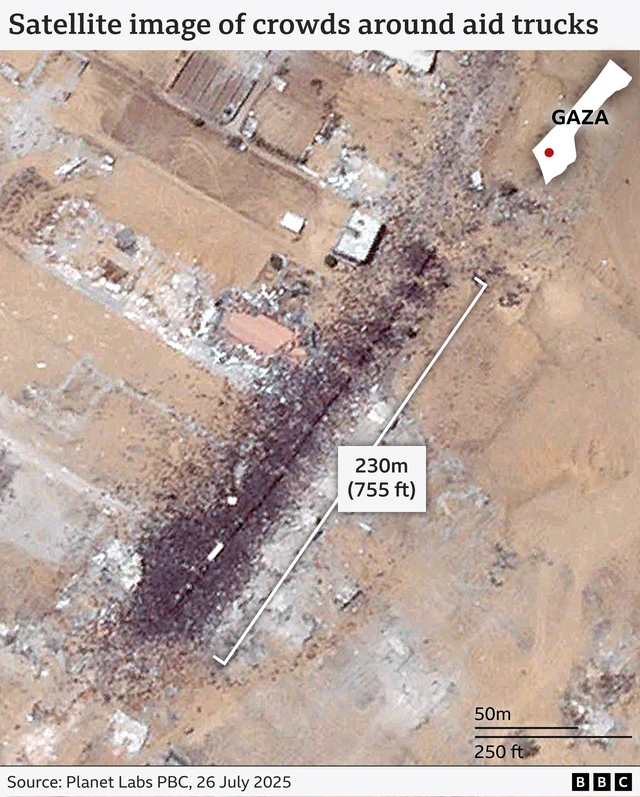 A satellite image. In the middle crowds of people can be seen surrounding about 15 aid trucks.