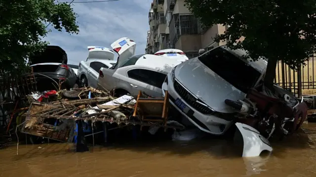 Cars piled up on top of one another, flooded in brown water