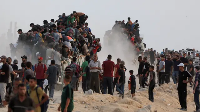People climb on top of trucks carrying aid