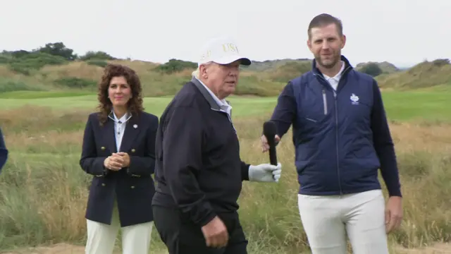 Trump with his son who hands him a mic as a woman stands in the background.
