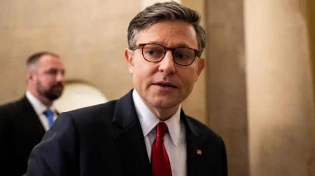 Mike Johnson wearing a dark suit and red tie