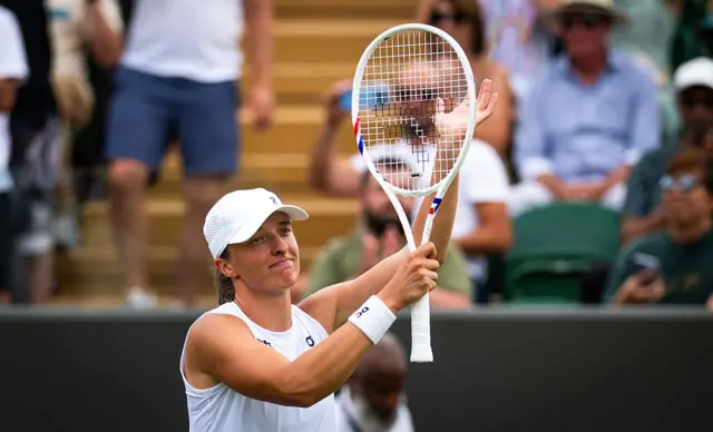 Iga Swiatek holds up her tennis racquet