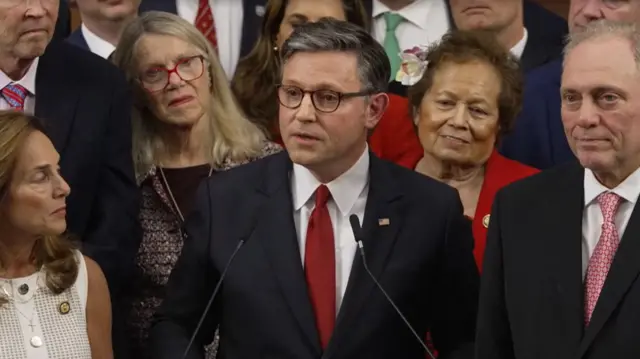 Mike Johnson surrounded by his colleagues while speaking