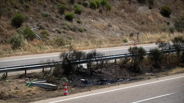 A burnt-out patch of grass, with a traffic cone in front of it