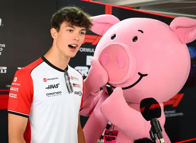 Oliver Bearman stands in the media pen with Percy Pig