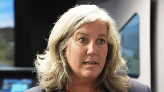 A headshot of Heidi Alexander, wearing a dark blazer