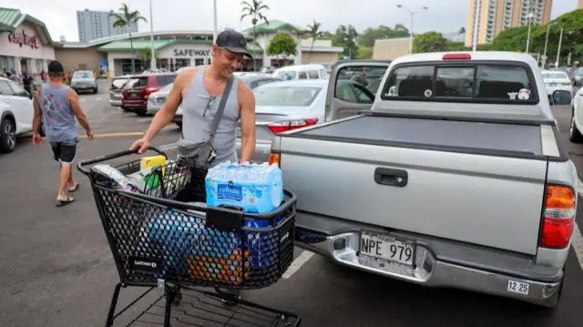 Honolulu resident Adam Jung loads water and other supplies into his vehicle