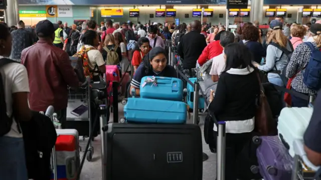 Passengers wait in line at Heathrow Airport, after radar failure led to the suspension of outbound flights across the UK, in Hounslow, London