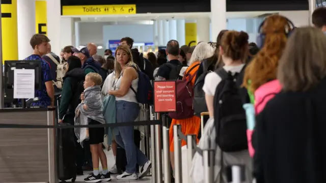 Passengers queue to board a flight at Gatwick Airport in Crawley,