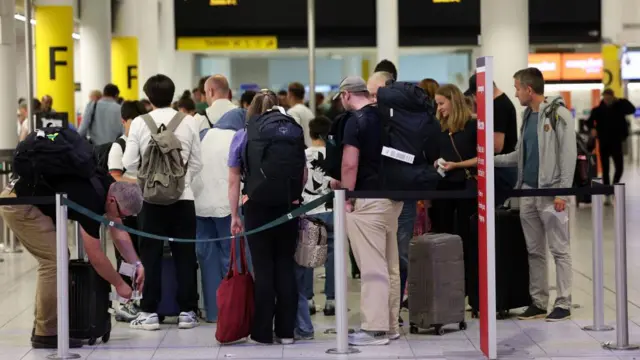 Several passengers waiting in line at to check in at Gatwick Airport