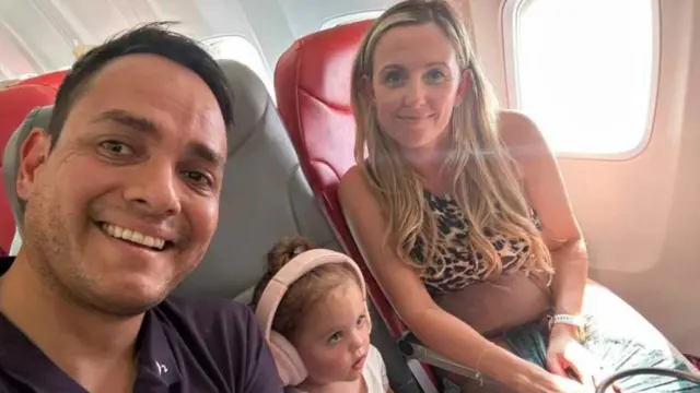 A selfie of Kirk Ryan, his wife and daughter sitting on seats on a plane