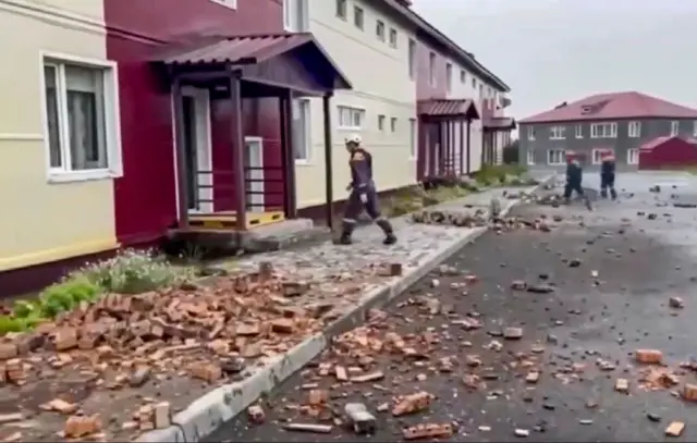 A still image taken from a handout video provided by the Russian Emergencies Ministry shows rescuers walking among debris in front of a damaged building following an earthquake, in Petropavlovsk-Kamchatsky, Kamchatka Krai