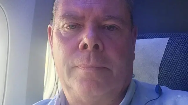 Robin Ilott looks to camera as he takes a selfie on a plane - he doesn't look thrilled