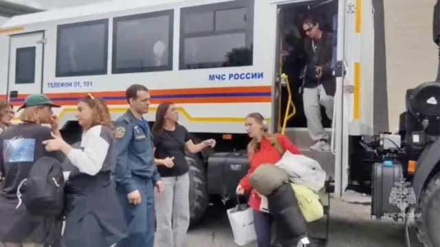 Evacuees walk out of a truck as rescuers relocate them to a safe area due to the tsunami threat following a powerful earthquake, in the region of Kamchatka, Russia,
