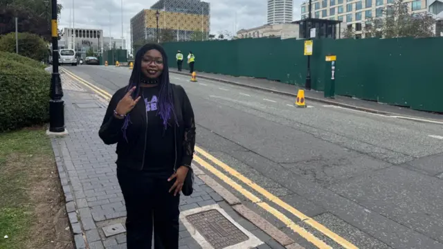 A woman stands outside on a road