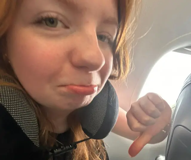 Asha on plane with thumbs down