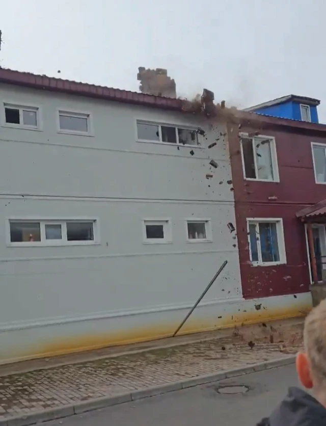 A still pic from a video. It captures a chimneys shakinh loose from their roofs.