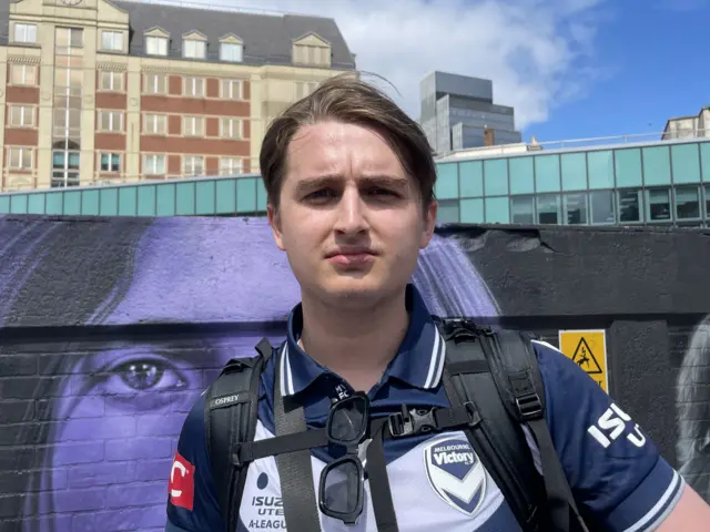 A man stands in front of the Black Sabbath mural