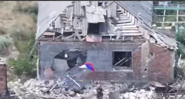Russia waved outside a destroyed house in Chasiv Yar