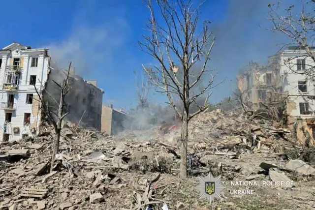 A photo from the National Police of Ukraine. It shows a couple of trees among lots of rubble and heavily-damaged buildings