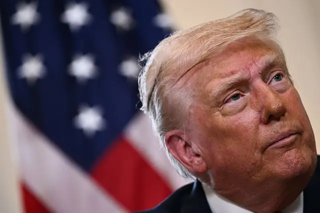 Close up of Trump looking up and to his left with US flag in background