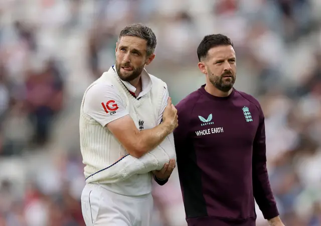 Chris Woakes walks off holding his shoulder