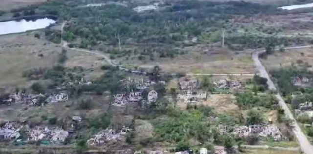 A still image from drone footage. Is shows a number of buildings heavily damaged and some destroyed.