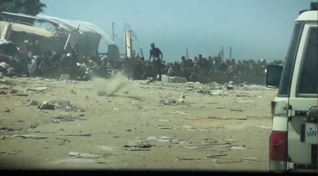 Video from the UN shows gunfire spraying in the sand very close to the feet of Palestinians waiting to get aid.