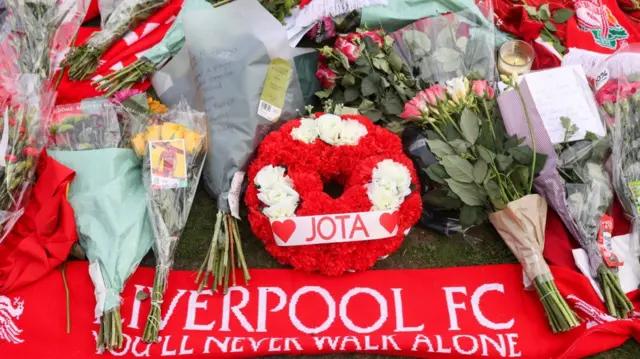 Floral tributes laid on patch of grass outside Anfield stadium in Liverpool