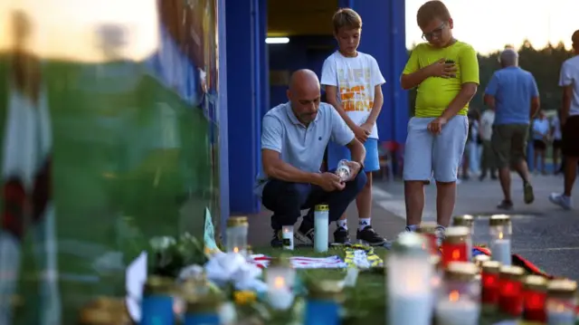 A man lights a candle in tribute to Liverpool's Portuguese soccer player Diogo Jota