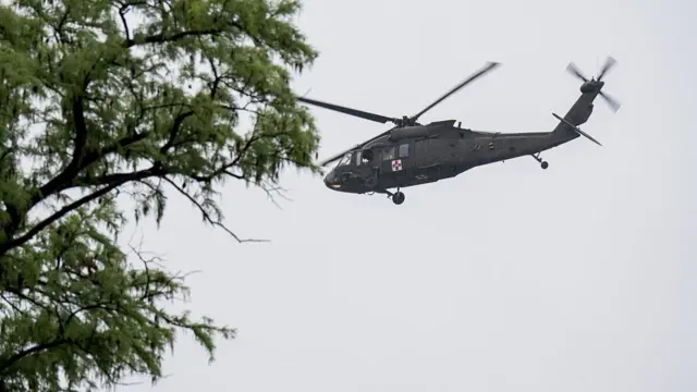 Helicopter in the sky, tree also in the right of the picture.