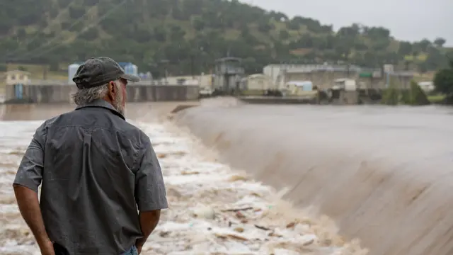 A man looks at a river with rising levels due to flooding