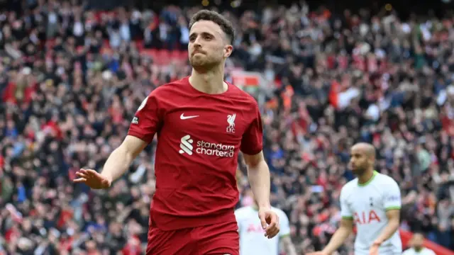 Diogo Jota in Liverpool red kit gestures to crowd during a match with Tottenham Hotspurs, fans blurred in the background