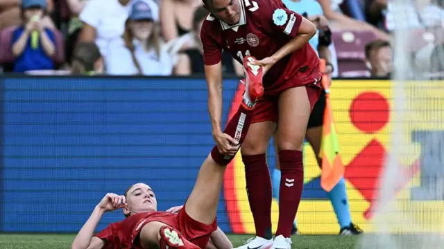 Denmark's defender #18 Sara Holmgaard (bottom) receives a massage from Denmark's defender #11 Katrine Veje during the UEFA Women's Euro 2025 Group C football match between Denmark and Sweden