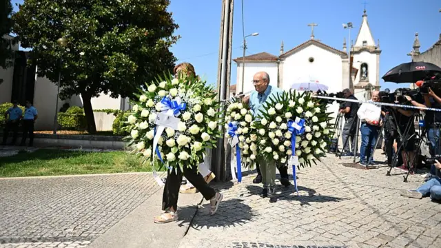 Two people carrying flowers gifted from Porto FC in front of the church
