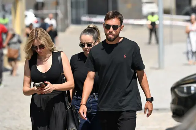 Ricardo Horta walks with two women wearing all black