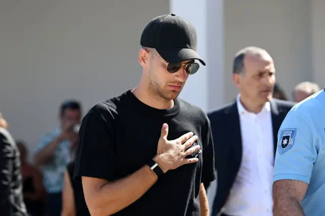 Diogo Dalot with his hand on his chest, wearing all black