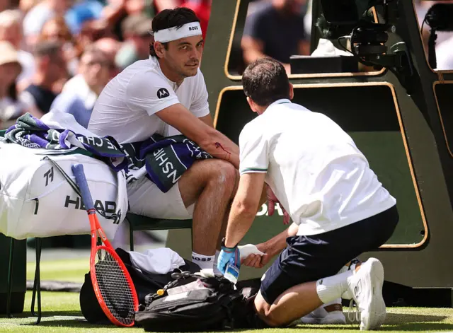 Taylor Fritz receives medical treatment to a cut on his elbow