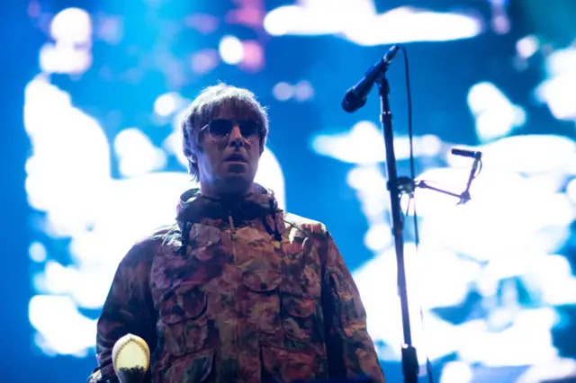 Liam Gallagher wearing a khaki parka jacket on stage in Australia in 2022