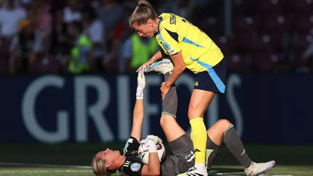 Linda Sembrant of Sweden helps to stretch the leg of teammate Jennifer Falk during the UEFA Women's EURO 2025 Group C match between Denmark and Sweden at Stade de Geneve