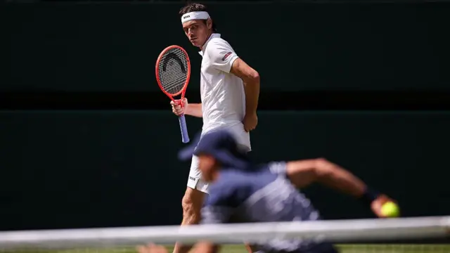 Taylor Fritz looks at a ball boy