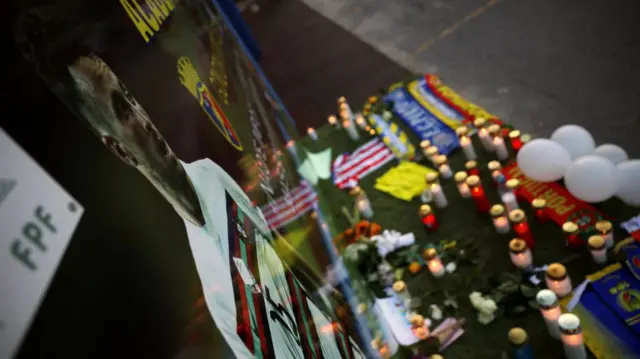 Candles and tributes laid in front of a poster of Diogo Jota