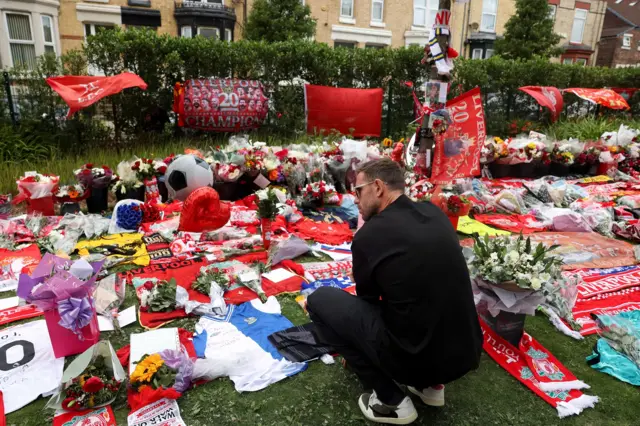 Jordan Henderson looks at floral tribute at Anfield