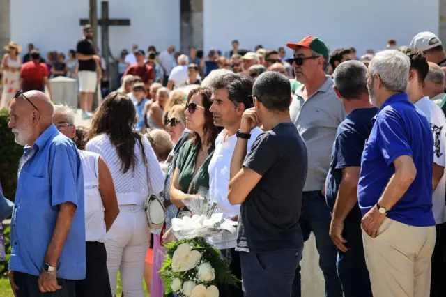 Members of the public stand with flowers by the chapel holding the pubic wake