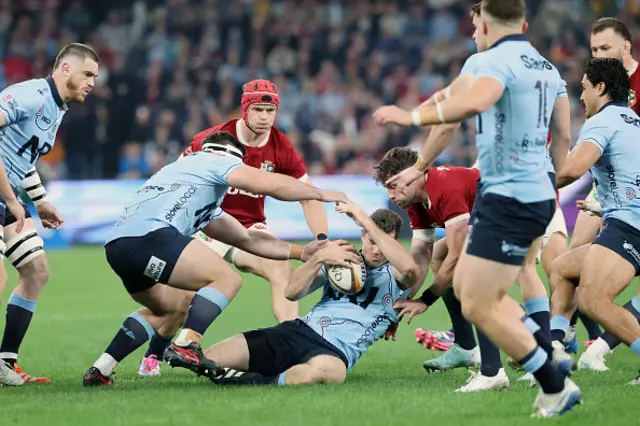 Waratahs' Lawson Creighton (C) is tackled by British and Irish Lions' Hugo Keenan