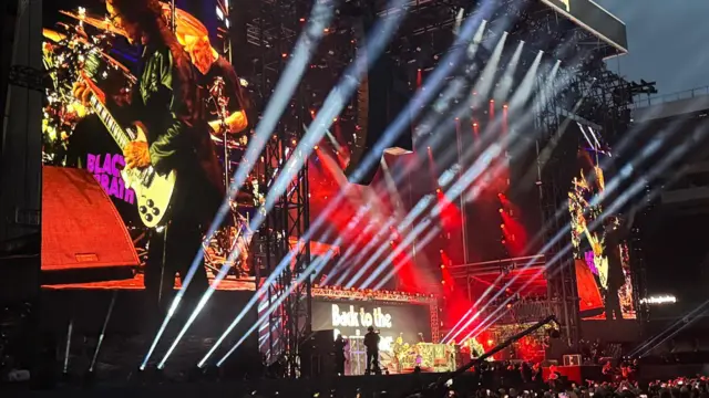 Lights shine out from a stage as a rock band take to it
